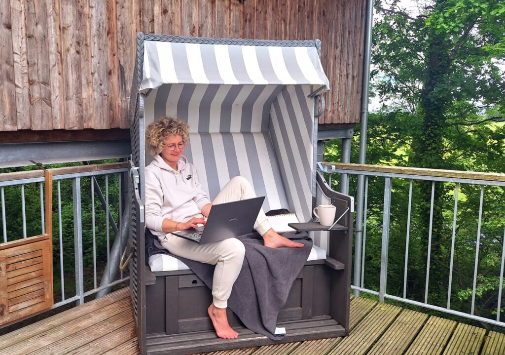 arbeitet im Strandkorb auf der Terrasse eines Baumhauses