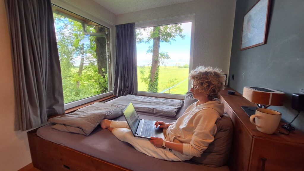 im Baumhaus auf dem Bett mit Laptop und Blick auf den Deich – Workation an der Nordsee