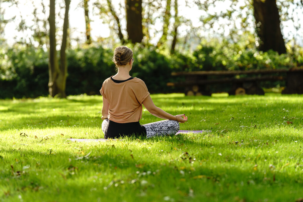 Gast praktiziert selbstständig Yoga auf der Wiese im Baumhaushotel Otterndorf